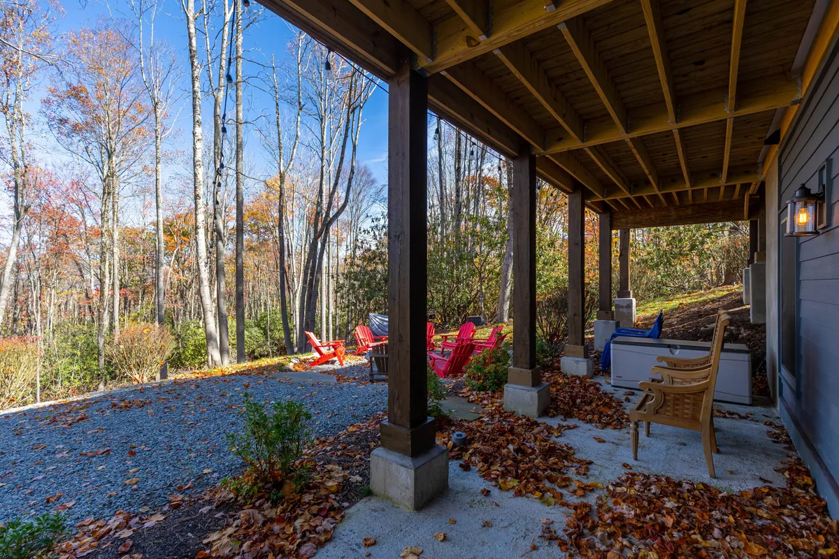 A cozy outdoor seating area with red Adirondack chairs placed under wooden beams, next to a gravel pathway. The setting suggests a place for relaxing after a day of exploration, enjoying sunsets, or gathering by an outdoor fire pit.