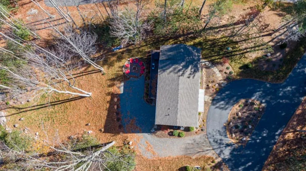 The exterior of the property with a prominent circular outdoor seating area, set against a peaceful natural backdrop. The driveway and well-kept grounds reinforce a sense of privacy and seclusion, ideal for gathering with loved ones or enjoying quiet, starlit nights.
